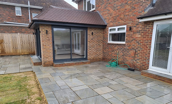 patio area with stone tiles and a glass extension featuring a modern design showcasing seven unique features of outdoor living