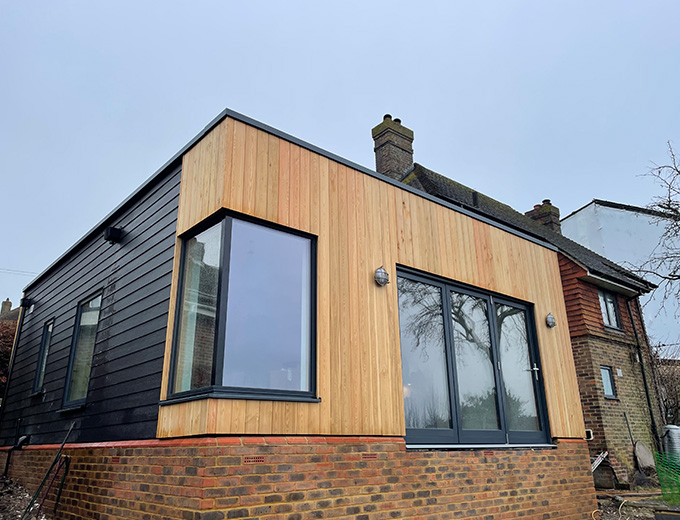modern architectural design featuring a wooden facade on a house with large windows and a contrasting dark side structure providing two distinct styles in residential building